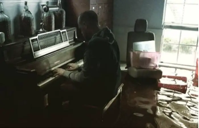 Pastor playing the piano in his flooded home